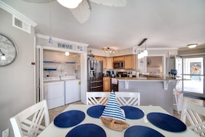 A modern kitchen with white appliances, wooden cabinets, and a central island.