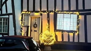 Une maison traditionnelle à colombages, avec une voiture garée devant.