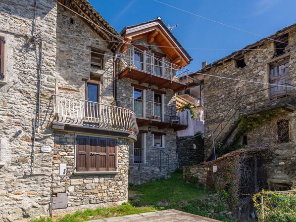 A stone building with a wooden balcony and a small garden area. - Stunning private villa for 4 guests with WIFI, TV, terrace and pets allowed (Peglio)