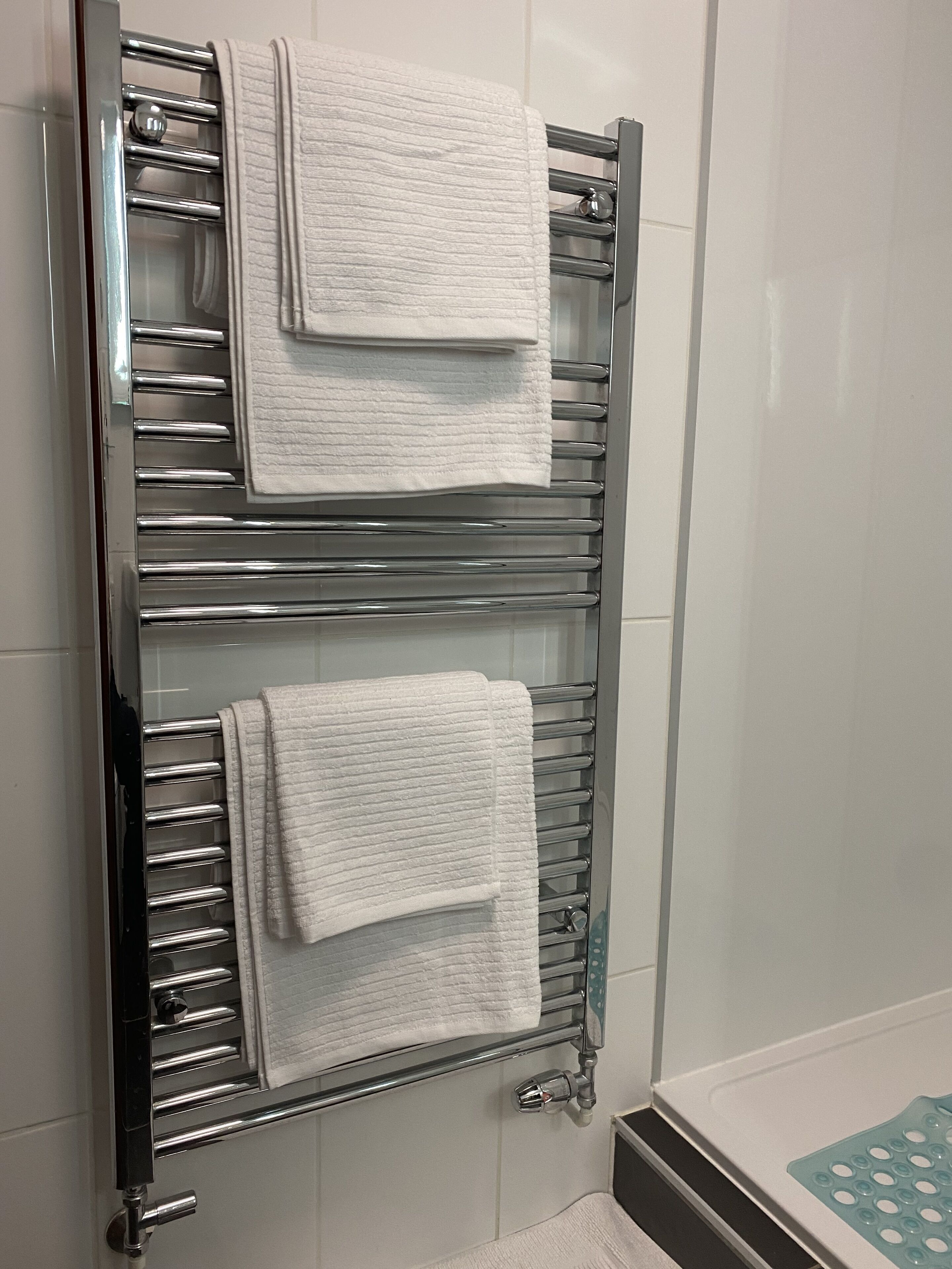 Une salle de bain avec un porte-serviettes chromé sur lequel sont pliés deux serviettes.