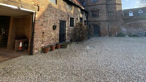 A courtyard with a gravel ground, a brick building with a tower, and a bike parked nearby. - Bellfosters (King's Lynn)