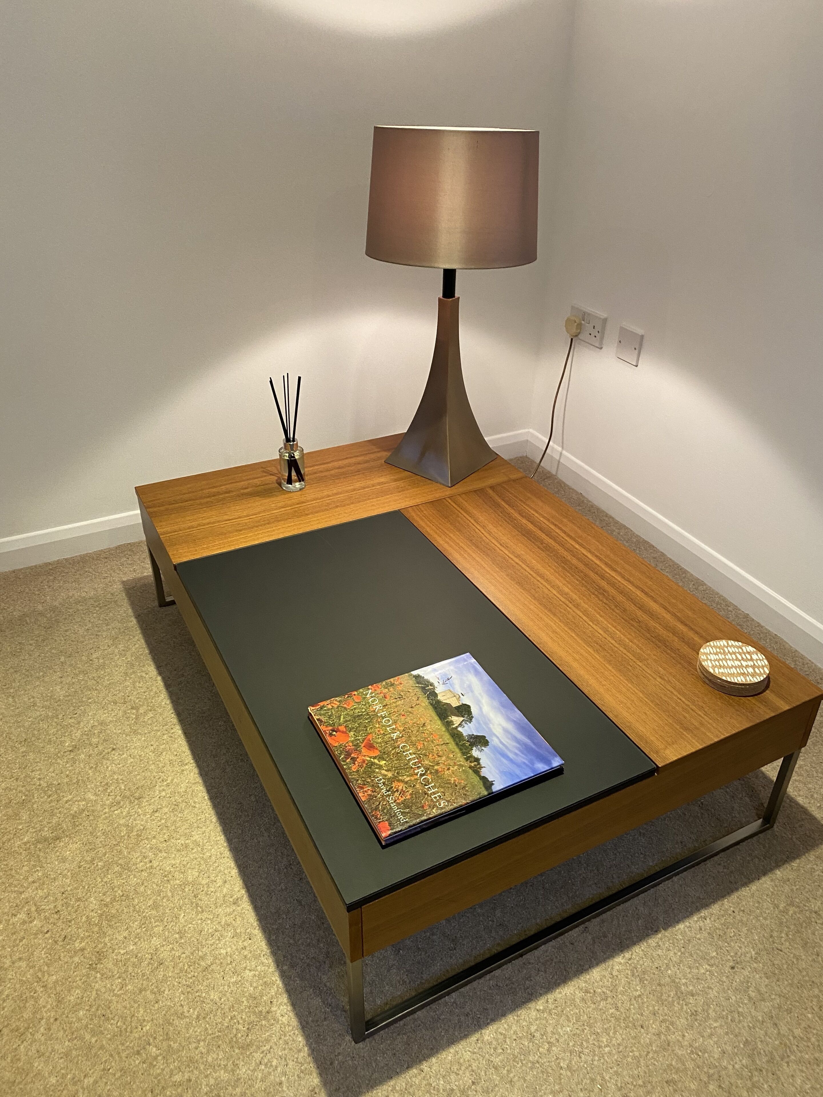 Une chambre moderne avec une table basse en bois, une lampe et un livre.