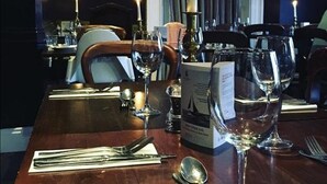 A dining table set with wine glasses, a candle, and a menu box. - Bellfosters (King's Lynn)
