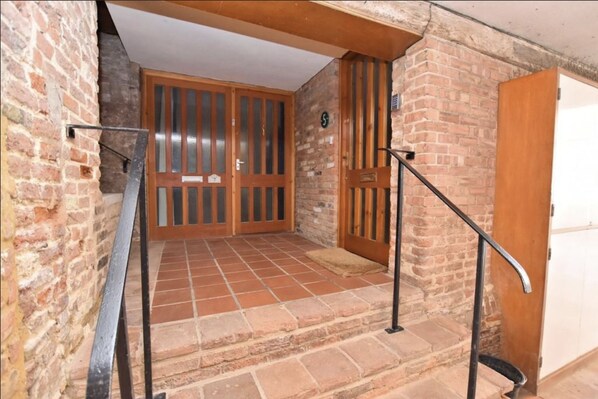 A staircase with a metal handrail leading to a wooden door with a number plate. - Bellfosters (King's Lynn)