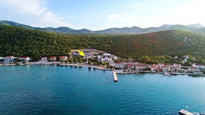 Un pueblo costero con casas a lo largo de la costa, un muelle y montañas al fondo.