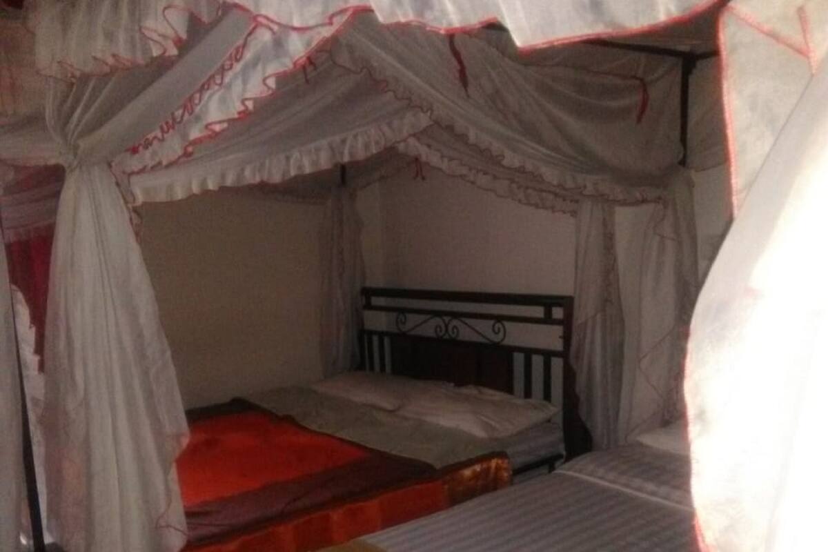 A room with a canopy bed, a single bed, and a bench.