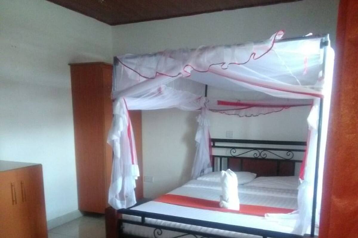 A single bed with a canopy, a wooden wardrobe, and a tiled floor in a room.
