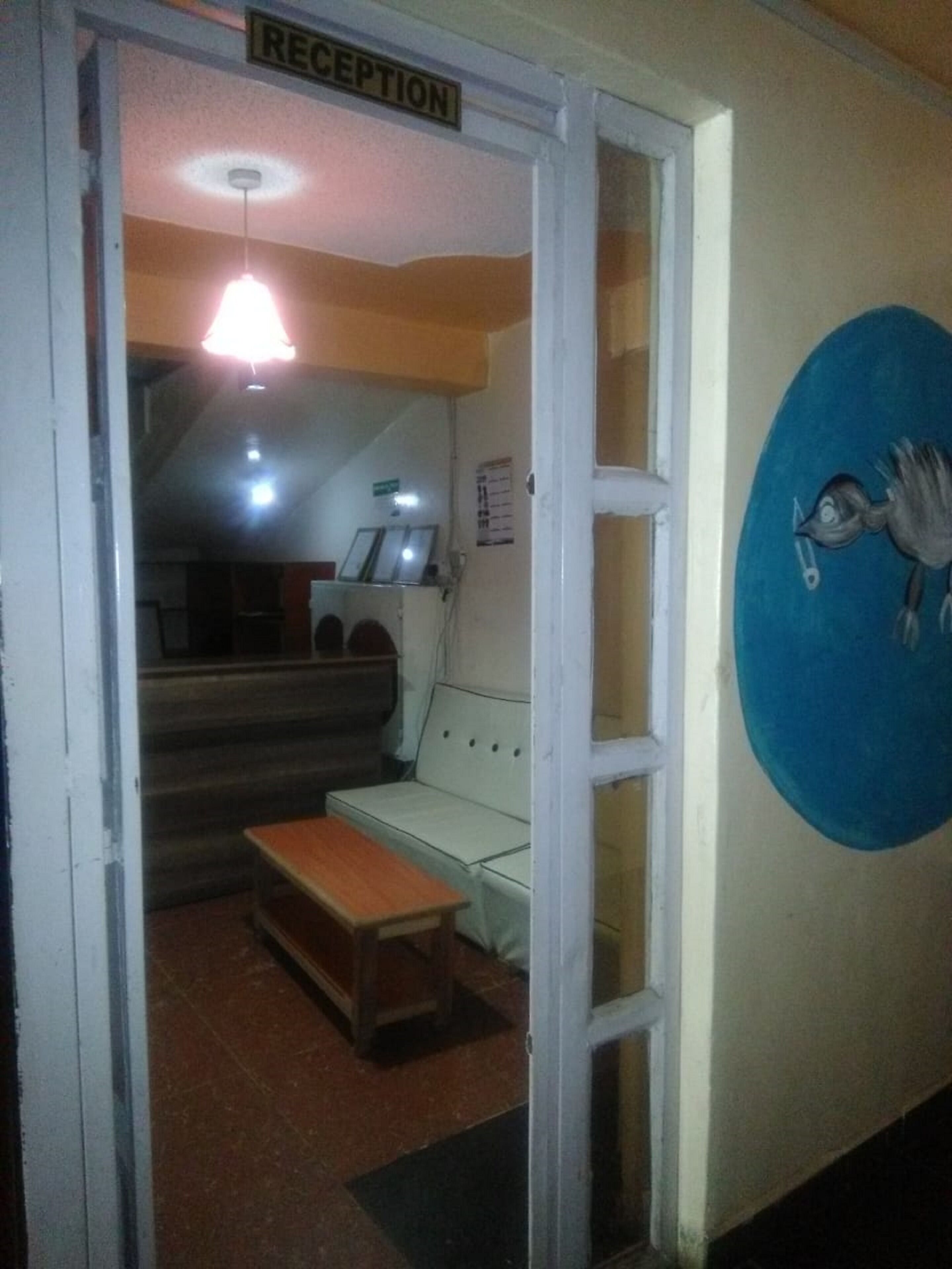 Zona de recepción con mostrador, un banco, un sofá y una pared con una obra de arte circular.