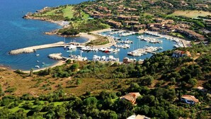 A coastal marina with boats docked, surrounded by residential buildings and greenery. - Lovely apartment in villa for 6 guests with A/C, pool, TV and terrace (San Teodoro)