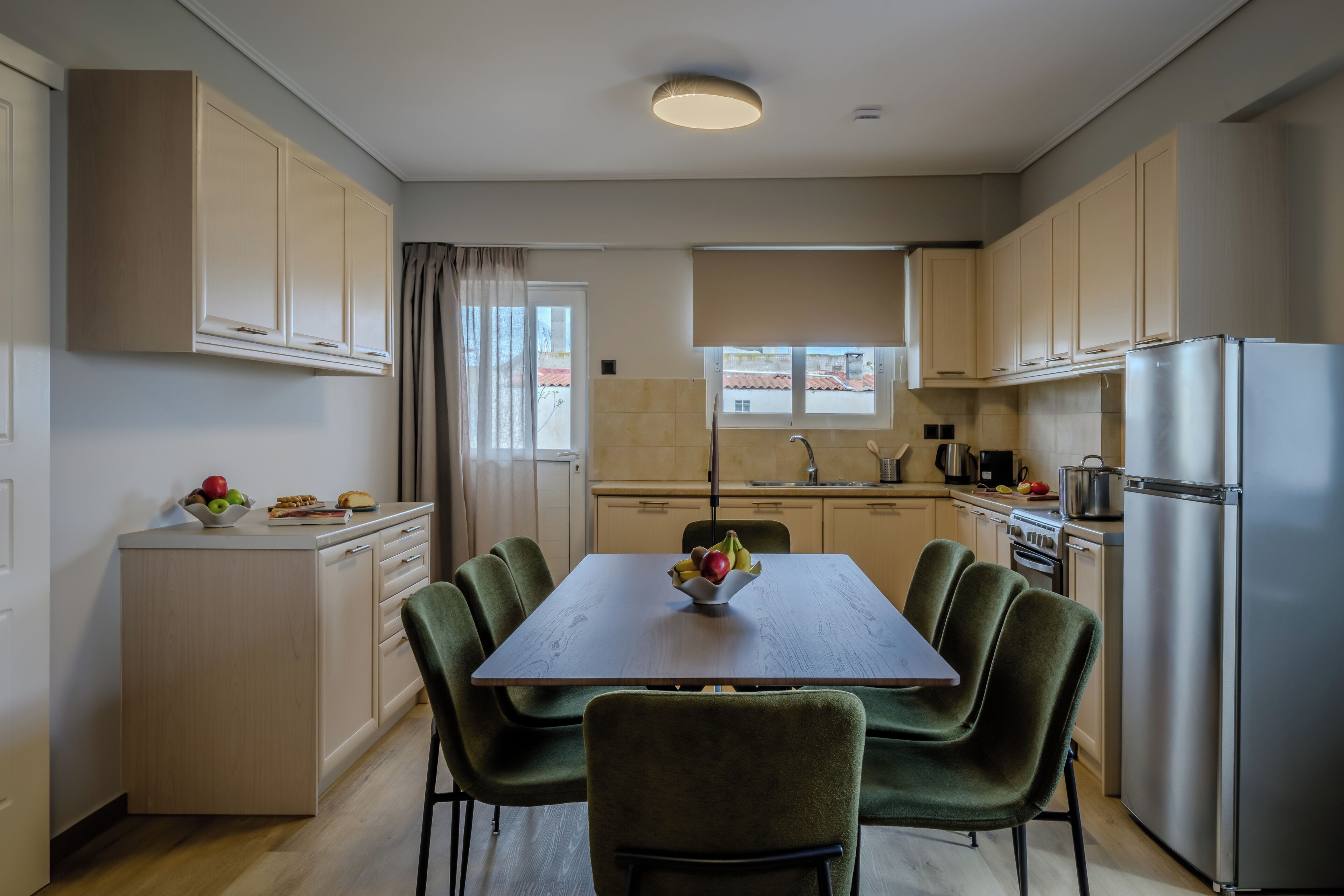 A modern kitchen with a dining table, chairs, cabinets, and a refrigerator.