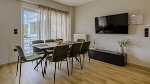 A modern dining area with a table, chairs, a TV, and a radiator. - Elise Apartment Airport  by Airstay (Spata-Artemida)