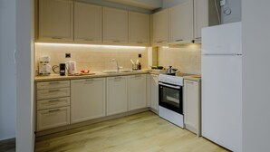 A modern kitchen with light-colored cabinets, a built-in oven, and a white refrigerator. - Elise Apartment Airport  by Airstay (Spata-Artemida)