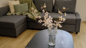 A modern living room with a dark wooden coffee table, a laptop, and a vase with flowers. - Elise Apartment Airport  by Airstay (Spata-Artemida)