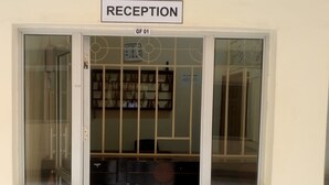 Une salle d’attente avec une enseigne au-dessus de la porte, une horloge et un grand objet circulaire posé sur le sol.