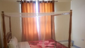 Un lit à baldaquin avec des rideaux, du linge de lit blanc et une couvre-lit à motifs floraux.