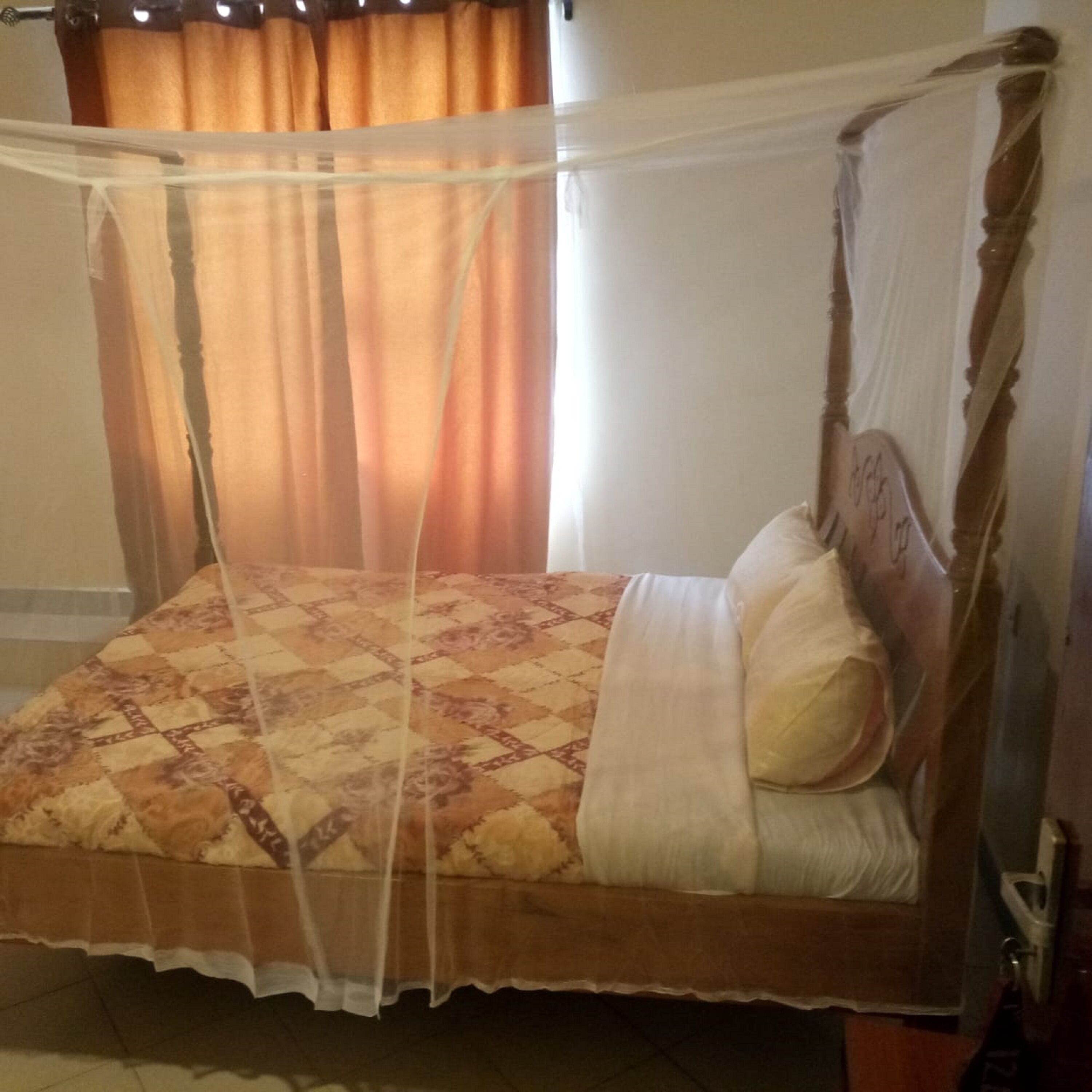 A bed with a canopy, a patterned bedspread, and pillows.