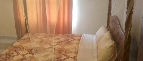 A bed with a canopy, a patterned bedspread, and pillows.