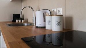 A kitchen with a stainless steel sink, a coffee maker, and two containers labeled "Sweet Home Coffee" and "Sweet Home Sugar". - Anivia Apartment Airport by Airstay (Spata-Artemida)