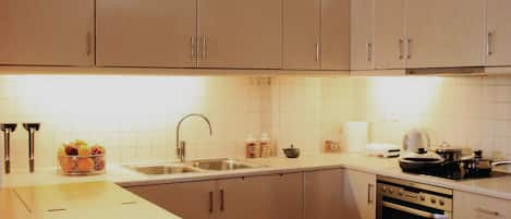 A modern kitchen with wooden cabinets, a stainless steel sink, and a built-in oven.