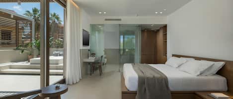 A modern hotel room with a large bed, a desk, and a balcony with plants.