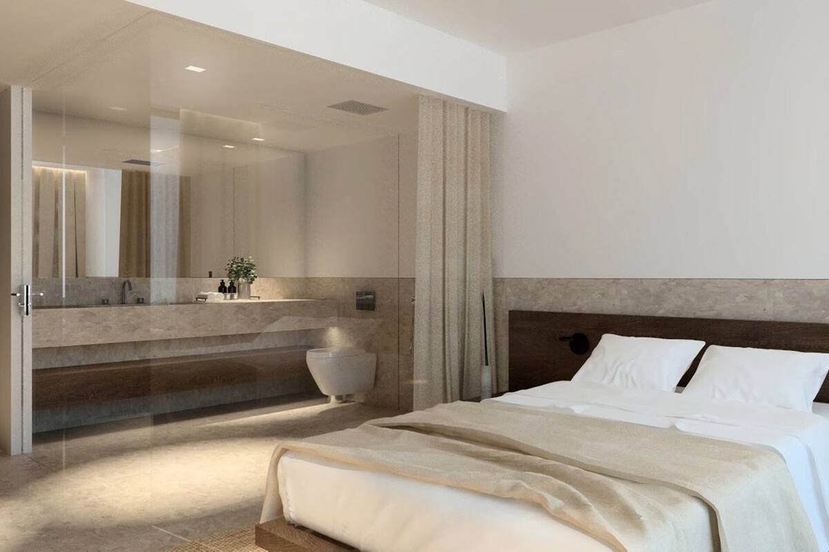 Ein modernes Schlafzimmer mit einem großen Bett, einem Badezimmer mit einer Badewanne und einem großen Spiegel.