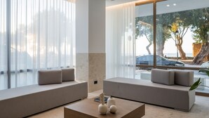 Ein modernes Wohnzimmer mit zwei Sofas, einem Couchtisch und großen Fenstern mit durchsichtigen Vorhängen.