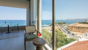 Ein Balkon mit Meerblick, ein Tisch mit einem Getränk und zwei Stühle.
