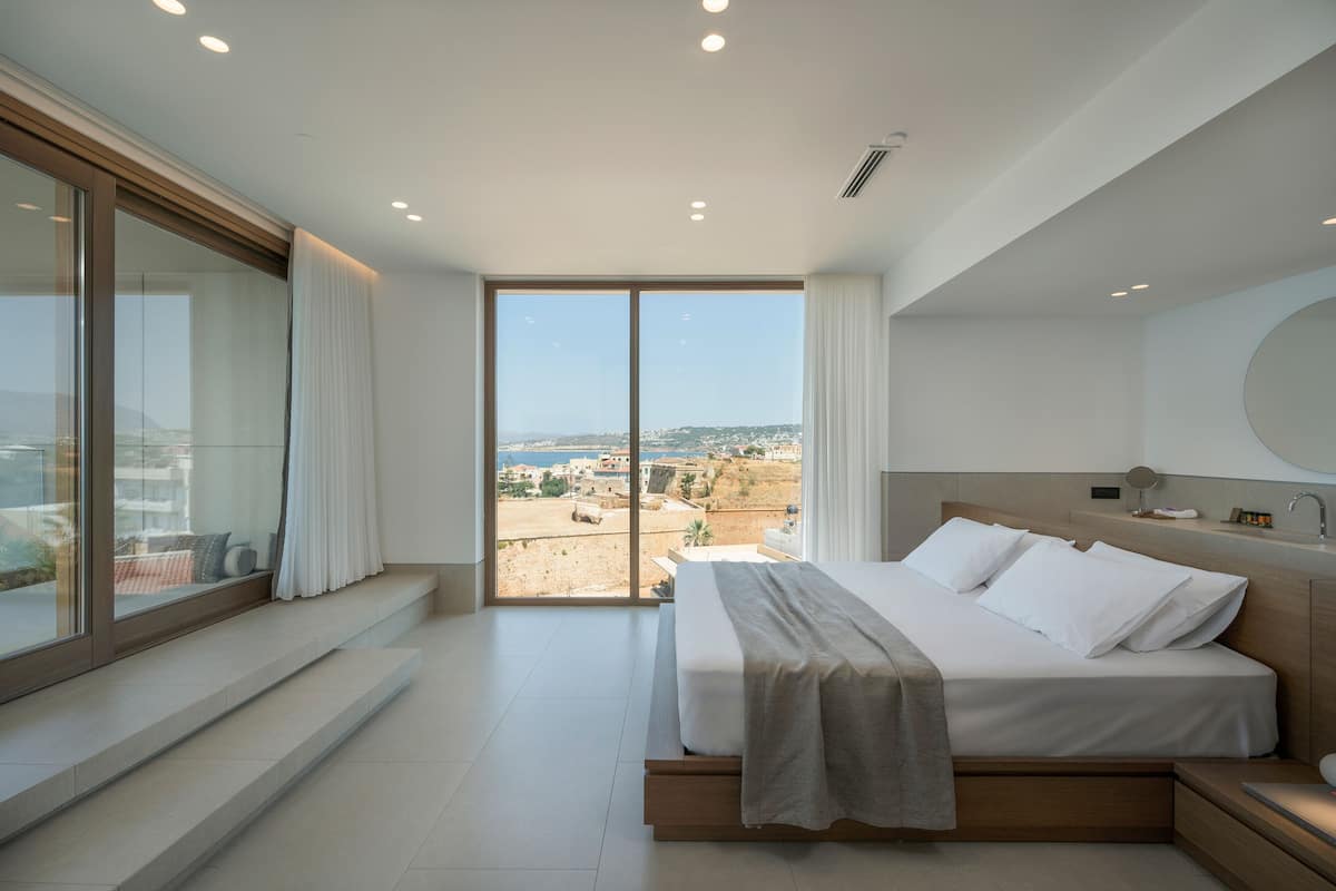 Ein modernes Schlafzimmer mit einem großen Bett, Blick auf die Stadt und einem Balkon.