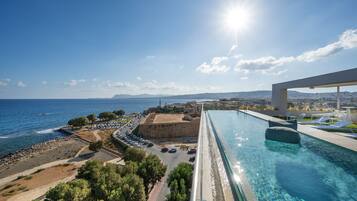 Piscina con vista al mar y zona de estacionamiento.