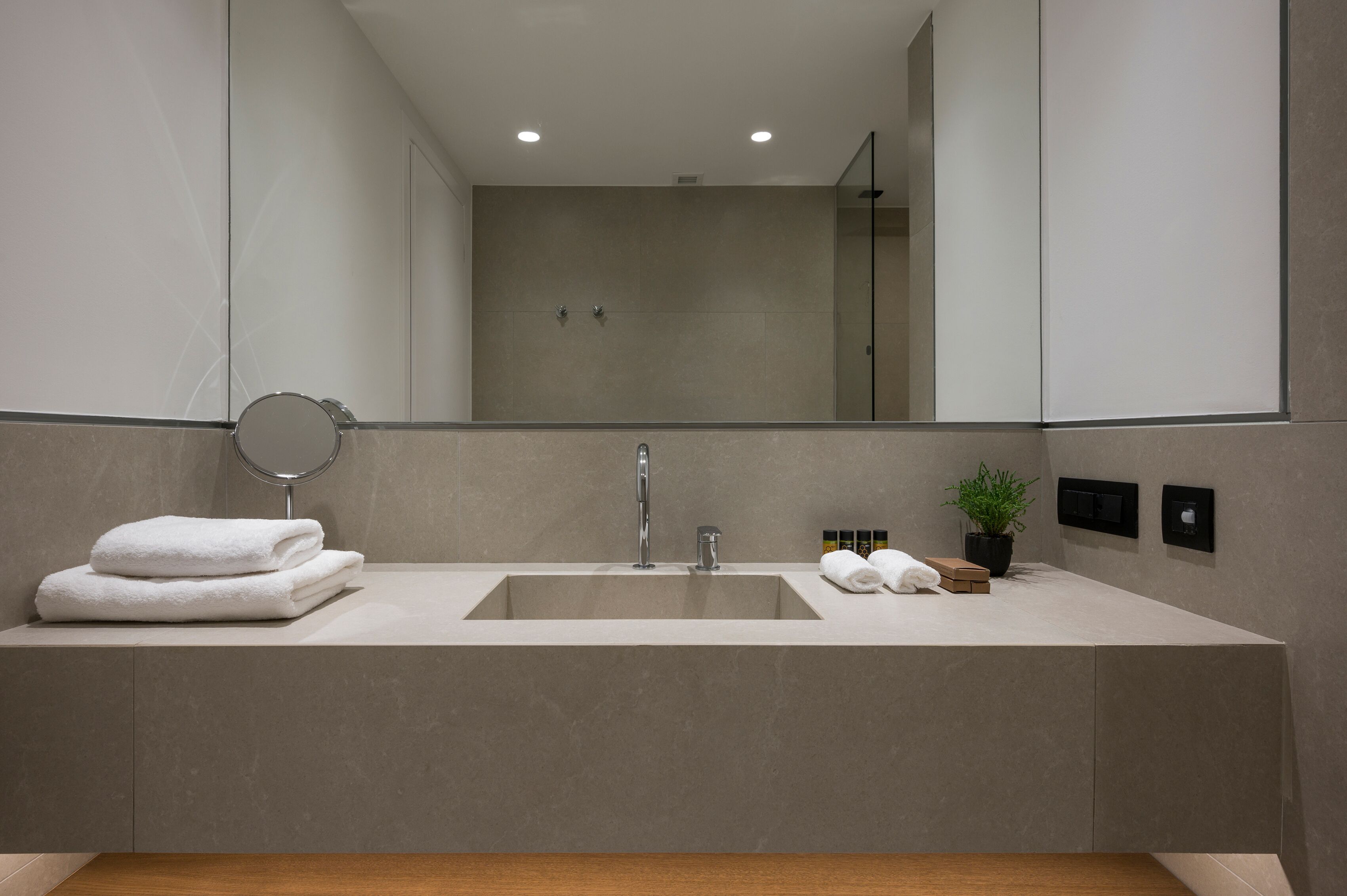 Un baño moderno con un espejo grande, un lavamanos y una ducha.