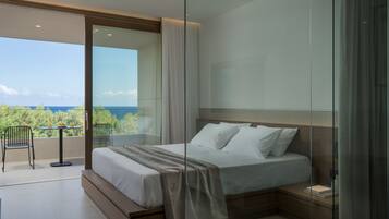 Un dormitorio moderno con una cama grande, un ventanal que da a un balcón y vistas al mar.