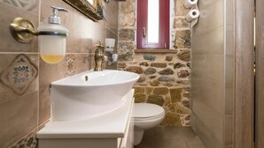 Un baño con un lavamanos blanco, un inodoro y una pared de piedra.