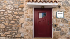 Un edificio de piedra con una puerta roja, un letrero que dice Orianna Apartment y una pequeña ventana sobre la puerta.