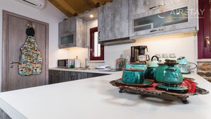 Una cocina moderna con encimera blanca, microondas, cafetera y teteras decorativas.
