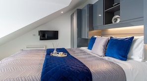 Une chambre moderne avec un grand lit, un téléviseur à écran plat fixé au mur et des placards intégrés.