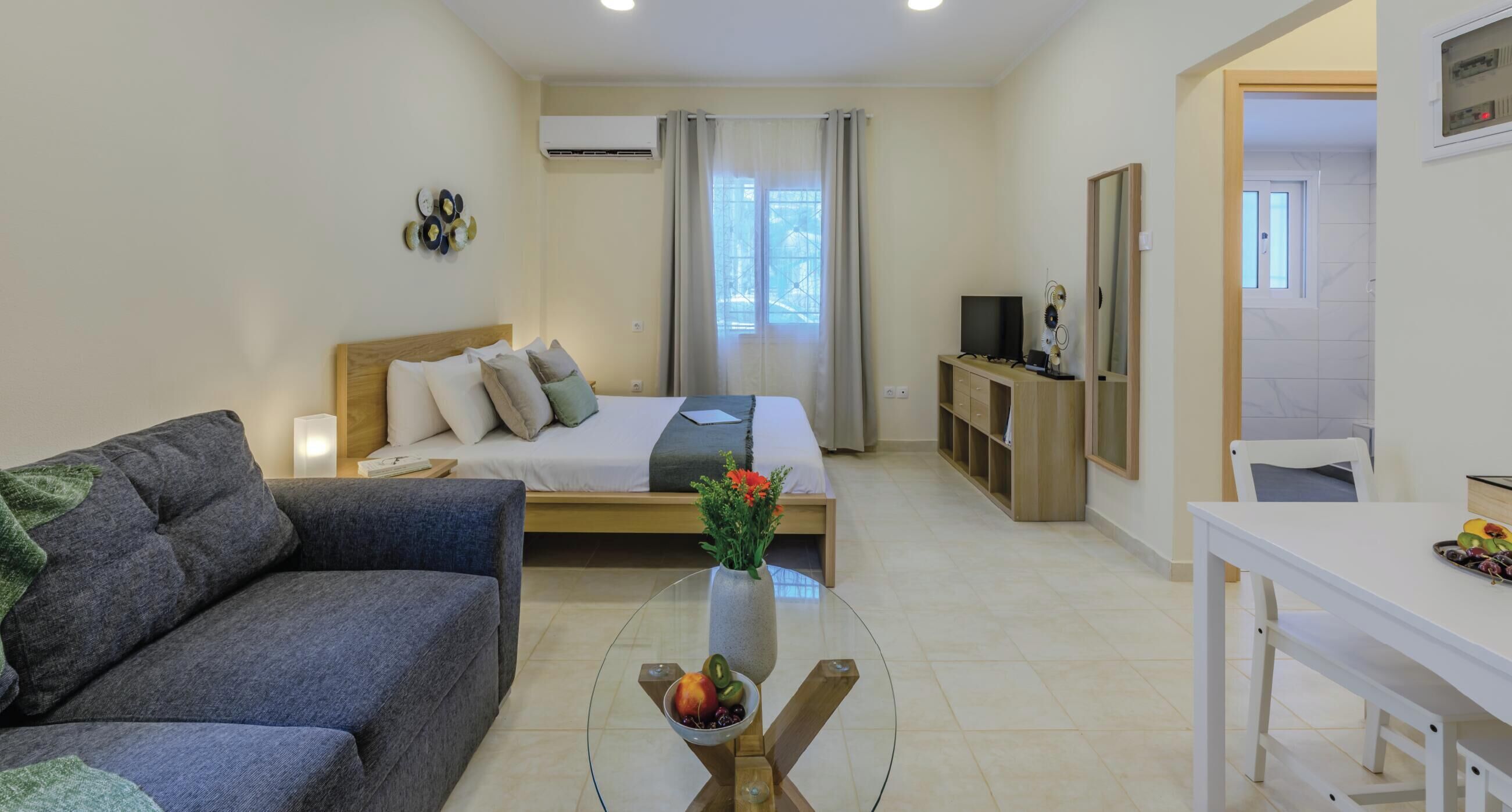 Una habitación de hotel moderna con una cama, un sofá, una mesa de comedor y un televisor.