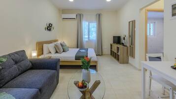 Una habitación de hotel moderna con una cama, un sofá, una mesa de comedor y un televisor.