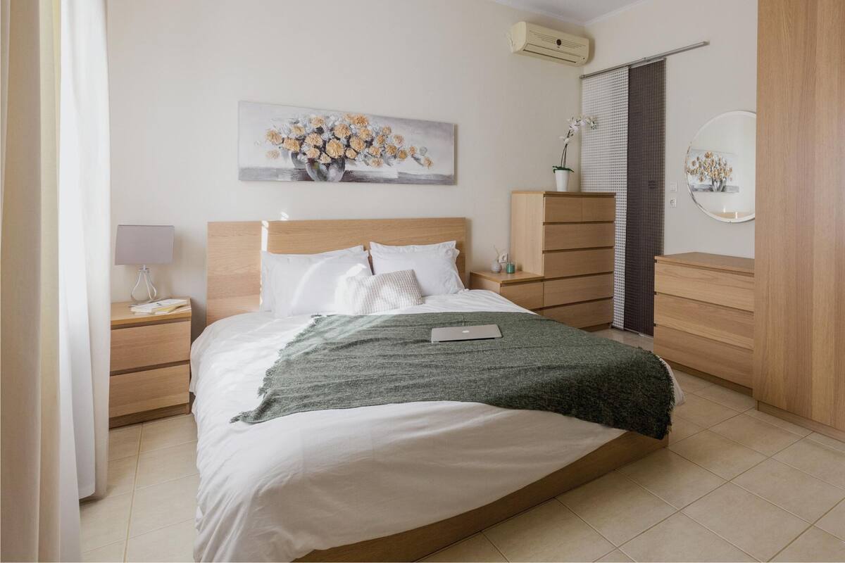 A modern bedroom with a bed, bedside tables, a dresser, and a mirror.
