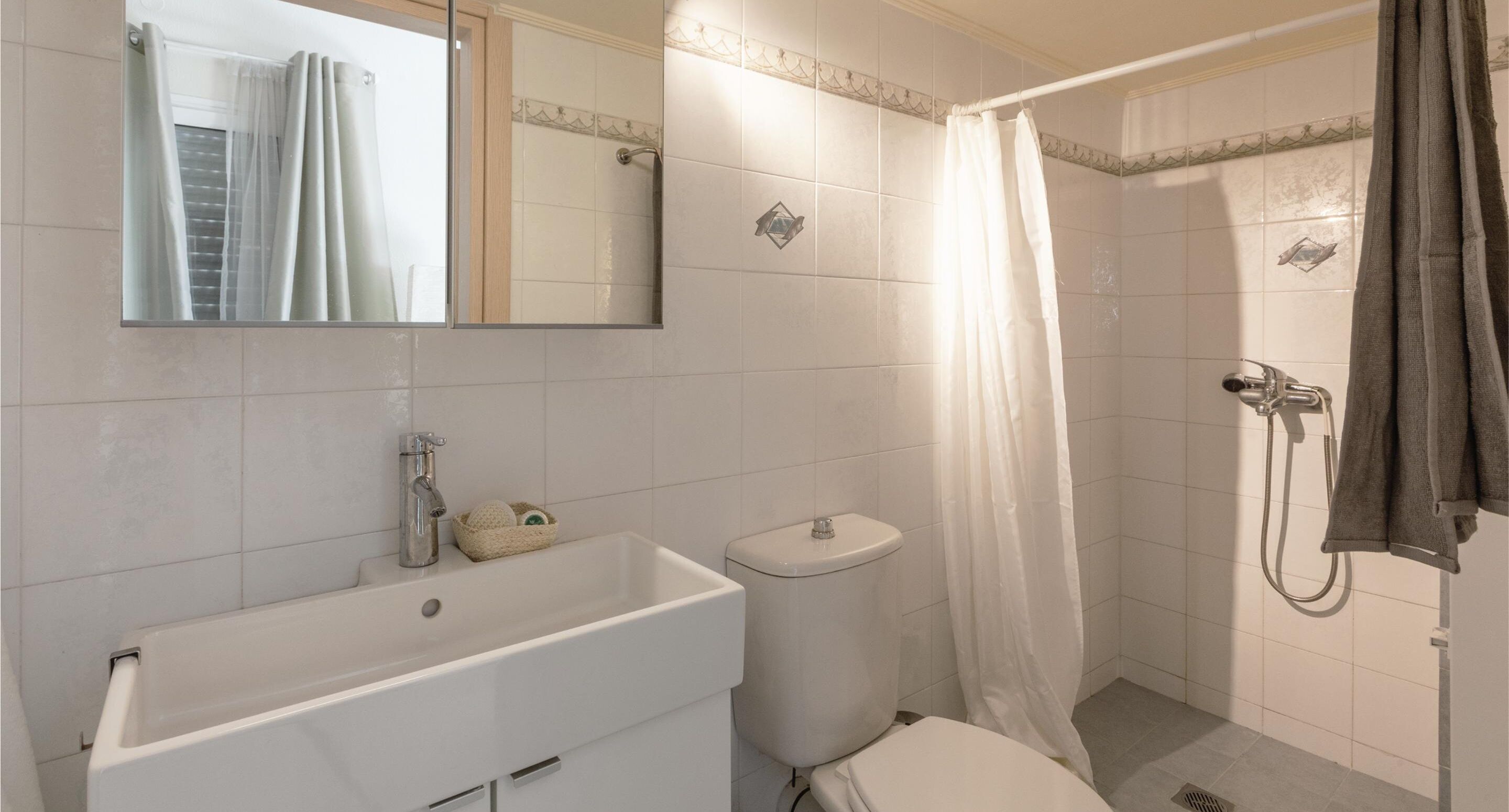 A bathroom with a white sink, toilet, and shower area.