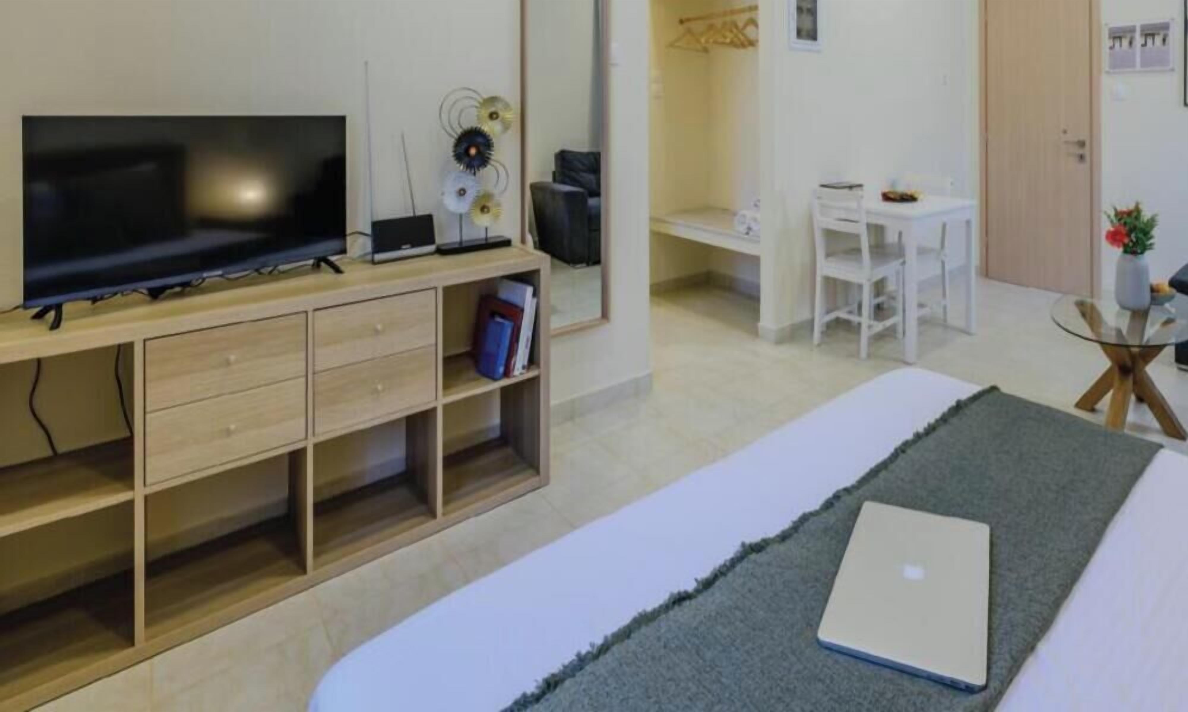 Une chambre à coucher avec un lit, un ordinateur portable, une télévision, un bureau et une chaise.