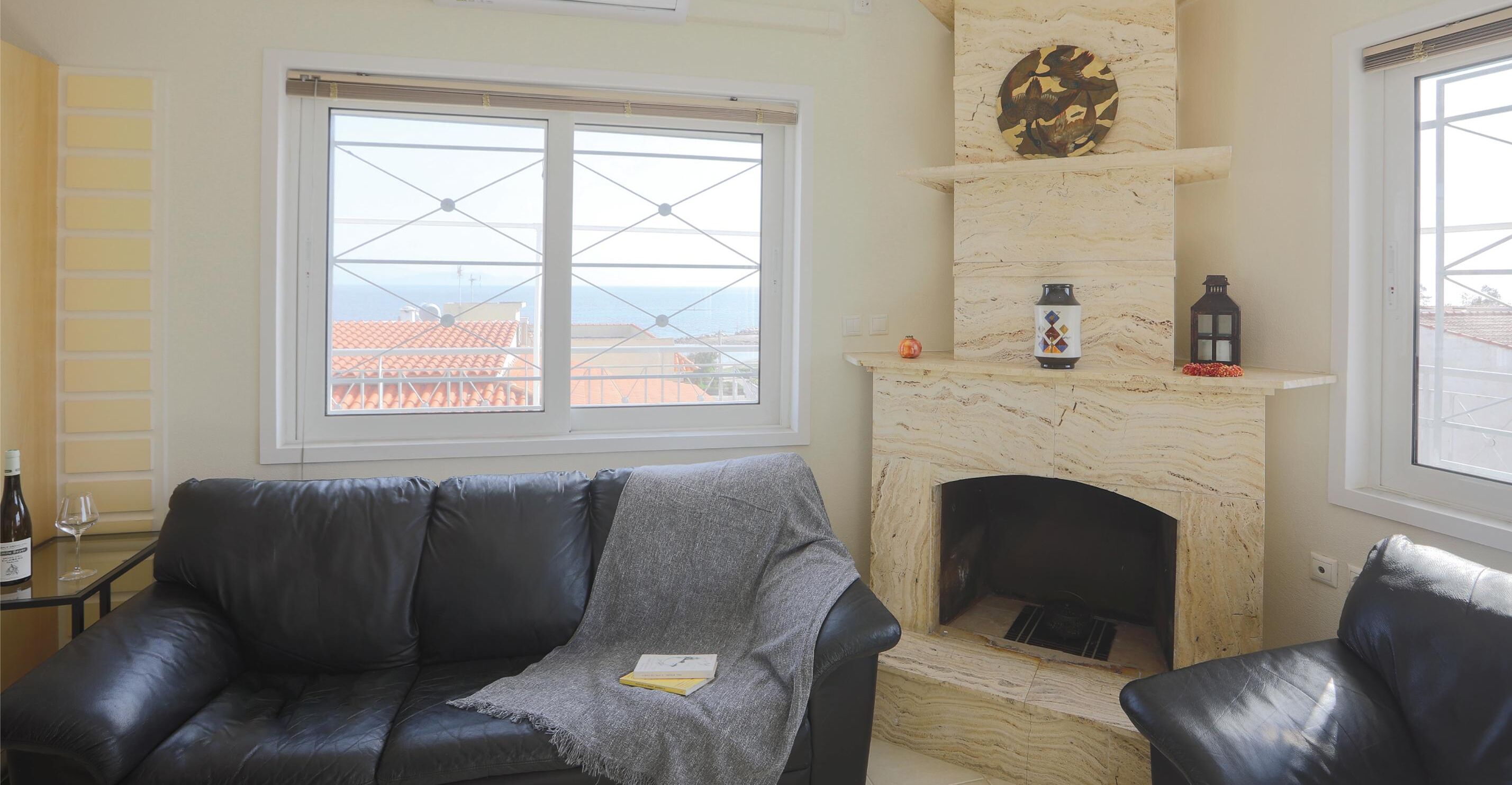 Un salon avec une cheminée, un canapé et une vue sur la mer par une fenêtre.