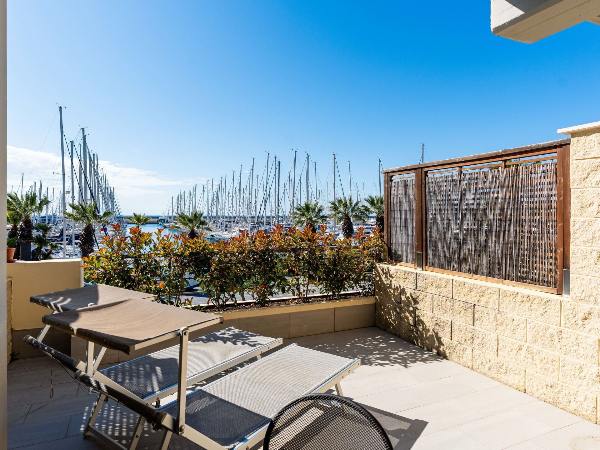 Una terrazza con vista sul porto turistico, arredi esterni e un muro in pietra.