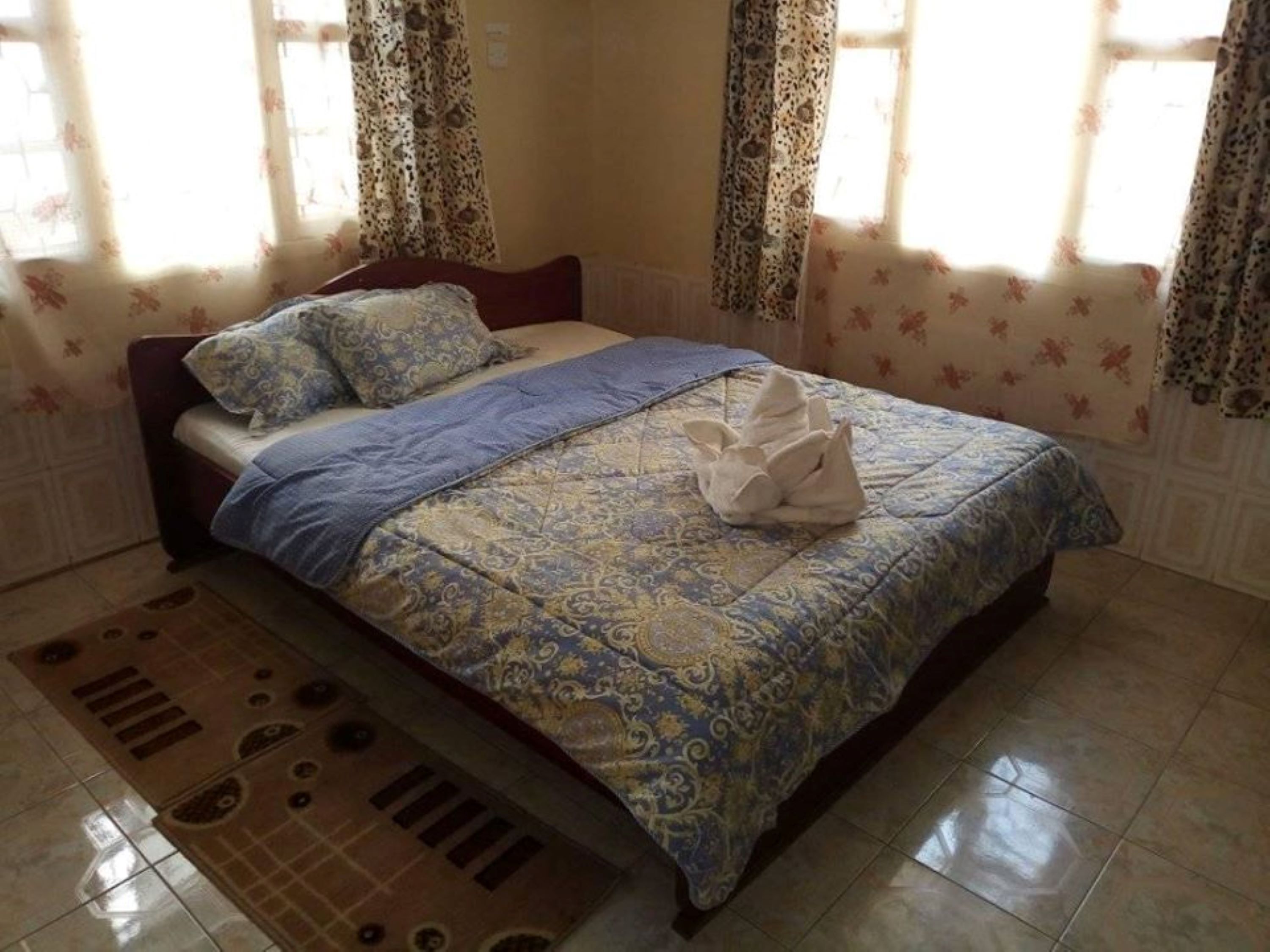 A bedroom with a bed, patterned bedspread, and curtains.