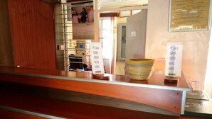 A reception desk with a wooden counter, a glass partition, and a sign instructing to drop keys. - St. Anna Guest House (Kisumu)