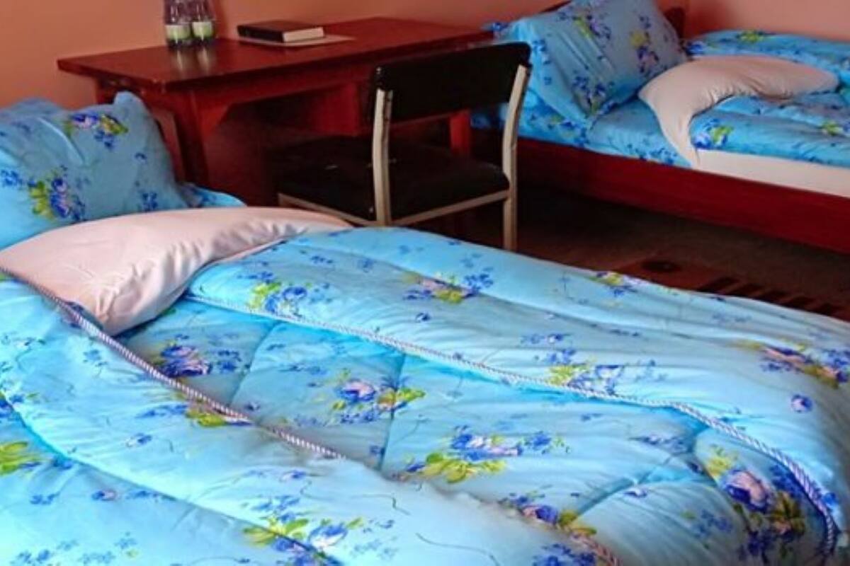 Un dormitorio con dos camas, cada una con ropa de cama y almohadas estampadas con motivos florales. Hay una mesita de noche de madera con una lámpara y un libro.