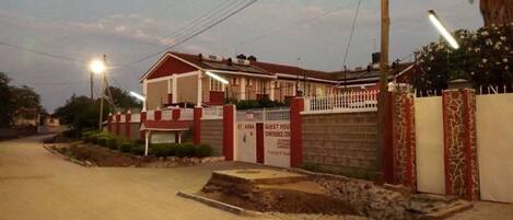 Una casa de huéspedes con fachada roja y blanca, entrada protegida por una reja y un letrero que indica que es un centro de conferencias.