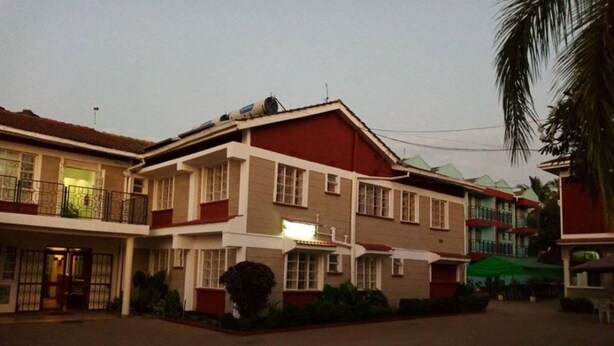 A multi-story hotel with a central courtyard, featuring balconies and a green umbrella. - St. Anna Guest House (Kisumu)