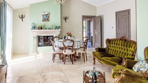 Un coin repas avec une table dressée pour quatre personnes, un canapé vert et une cheminée avec une étagère au-dessus.