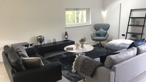 A modern living room with a black sofa, grey armchair, and a coffee table. - An Caisteal Lodge With Cascading Waterfall View (Crianlarich)