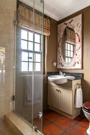 A bathroom with a glass-enclosed shower, a sink with a mirror, and a toilet.